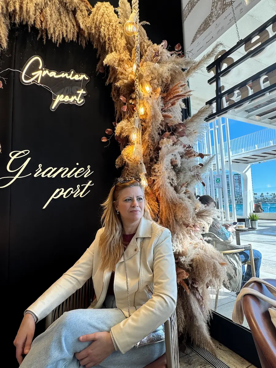 Priscilla Simoni sentada em um ambiente com decoração floral